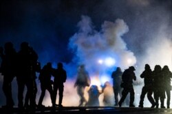 FILE - Authorities fire gas munitions at demonstrators gathered outside the Brooklyn Center Police Department to protest the shooting death of Daunte Wright, in Brooklyn Center, Minn., April 13, 2021.