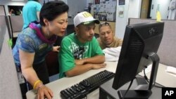 Career center specialist Sun Gaddis (L) helps job seeker Kaston Joshua (C), while Rudy Martin looks on at WorkSource Oregon, in Tualatin, Oregon, July 2012.