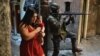 A woman walks with her baby past a PM militarized police soldier in position and aiming his rifle in Rocinha favela in Rio de Janeiro, Brazil on September 23, 2017. 