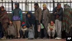 Impoverished and homeless people stand in a queue to receive free food from a volunteer organization in front of a temple, in New Delhi, India, January 1, 2013.