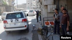 Residents watch as a convoy of U.N. vehicles carrying a team of United Nations chemical weapons experts drive past near one of the sites of an alleged chemical weapons attack in Zamalka, a suburb of Damascus on August 28, 2013. 