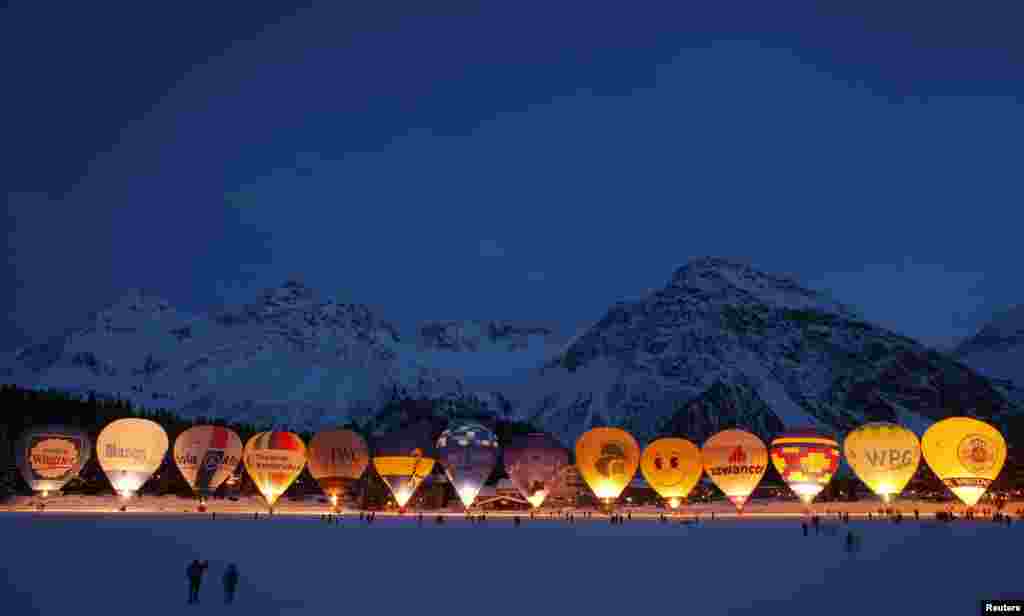 Spectators take pictures as hot air balloons are gathered on the frozen Upper Lake during International Balloon Week in the Swiss alpine resort of Arosa.