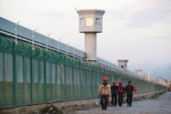 Workers walk by the perimeter fence of what is officially known as an education centre in Dabancheng, China on September 4, 2018