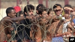 FILE - Cuban refugees hand notes with their names to Navy personnel so that they can get on the list of detainees at the Guantanamo Bay Naval Base in Cuba, Aug. 27, 1994. 