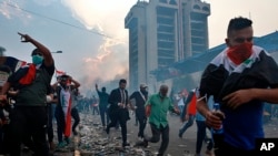 Anti-government protesters run to take cover while Iraqi Security forces fire tear gas during a demonstration in Tahrir Square in Baghdad, Iraq, Oct. 28, 2019. 