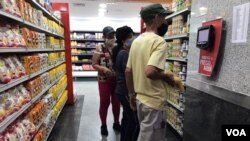 Ciudadanos consultan el precio de un producto en un supermercado en el este de Caracas, Venezuela. Febrero, 2021. Foto: Carolina Alcalde - VOA.