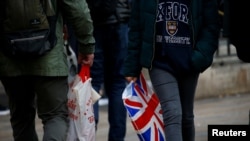 FILE - Shoppers carry shopping in plastic bags in the West End, in London, Britain, Dec. 27, 2018. 