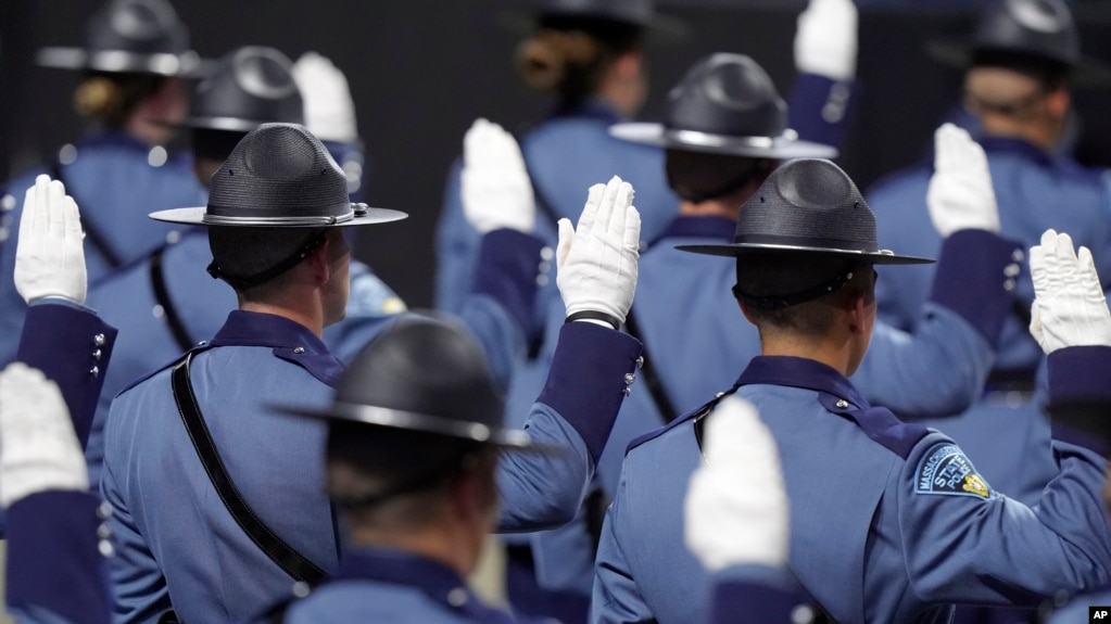 FILE - Members of the Massachusetts State Police 90th Recruit Training Group raise their hands as they are sworn in as State Police Troopers by Mass. Gov. Maura Healey, not shown, during ceremonies, Oct. 9, 2024, at the DCU Center, in Worcester, Mass.