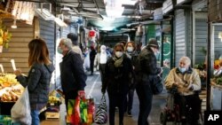 People wearing masks hold bags while shopping at an open-air market in Rome, Thursday, Oct. 22, 2020. Authorities in regions including Italy's three largest cities have imposed curfews in a bid to slow the spread of COVID-19 where it first struck…