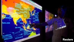 United States Navy lieutenant commander Kirk Benson, points at a map of the South China sea at the Tactical Flag Command Center (TFCC) of the 19,200-ton USS Blue Ridge in Manila, July 22, 2014.