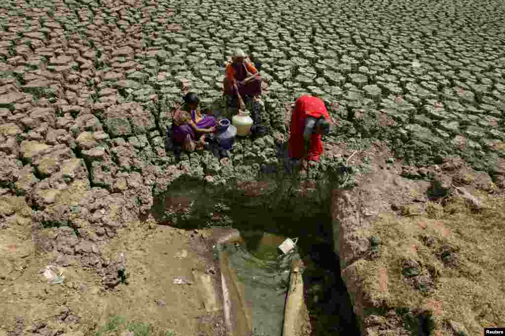 Women fetch water from an opening at a dried-up lake in Chennai, India.