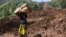 FILE: A woman carries a rolled-up mattress at a landslide site in Shisakali village of Bududa district, eastern Uganda, 6.6.2019