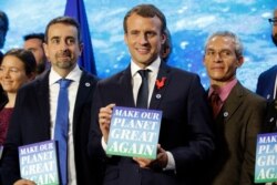 French President Emmanuel Macron holds a sign with the slogan 'Make our planet great again' as he attends the 'Tech for Planet' event at the 'Station F' start-up campus ahead of the One Planet Summit in Paris on Dec. 11, 2017.