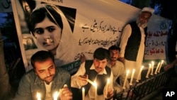 Pakistanis light candles in front of a banner showing a picture of 14-year-olschoolgirl Malala Yousufzai in Peshawar, Pakistan, Oct. 15, 2012. 