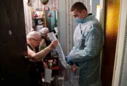 An elderly woman casts a ballot during municipal elections in Tomsk, Russia, Sept. 13, 2020.