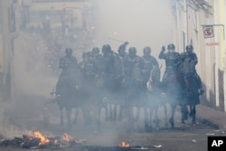 Mounted police cross a burning barricade in pursuit of anti-government demonstrators during a nationwide strike against President Lenin Moreno and his economic policies, in Quito, Ecuador, Oct. 9, 2019.