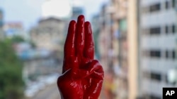 An anti-coup protester shows the three fingered salute of resistance on his red painted hand in memory of protesters who lost their lives during previous demonstrations in Yangon, Myanmar on Tuesday, April 6, 2021. 