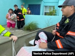 This photo provided by Venice Police Department rescue crews assist residents after conducting door-to-door wellness checks, in coastal areas flooded by Hurricane Helene on Sept. 27, 2024 in Venice, Florida. (Venice Police Department via AP)