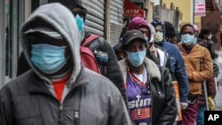 People wait for a distribution of masks and food in the Harlem neighborhood of New York, where the latest analysis shows nearly one-third of those who died from the coronavirus are African American, even though blacks are only about 14% of the population.