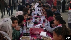 Palestinians sit at a large table as they gather for iftar, the fast-breaking meal, on the first day of Ramadan in Rafah, southern Gaza Strip, March 1, 2025.