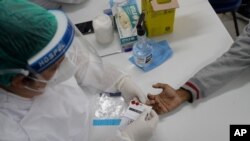 A health worker gives a resident a COVID-19 test on Vakcinacija u Brazilu