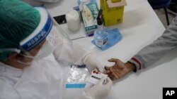 A health worker gives a resident a COVID-19 test on the first day of a three-day vaccination campaign for people over age 35 in the Complexo da Maré favela of Rio de Janeiro, Brazil, July 29, 2021.