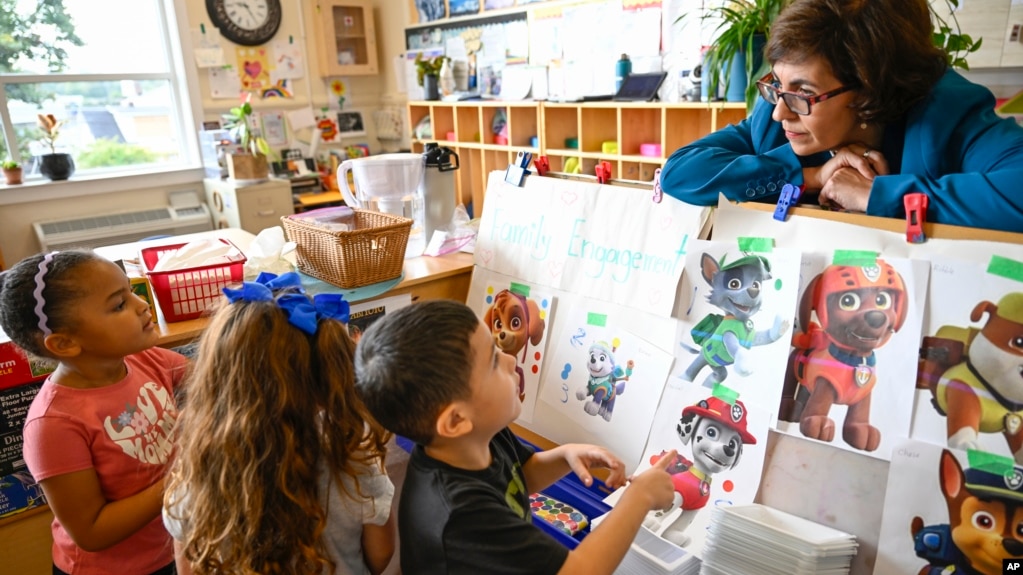 Preschool Executive Director Maria Isabel Ballivian, right, listens to her students on what characters of the TV show PAW Patrol they will vote for at the ACCA Child Development Center on Sept. 19, 2024, in Annandale, Virginia. (AP Photo/John McDonnell)
