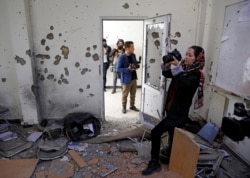 FILE - Afghan journalists film inside a classroom after yesterday's attack at the university of Kabul, Afghanistan, Nov. 3, 2020.