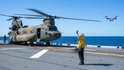 “美利坚”号两栖攻击舰上一名海军航空兵于“护身军刀25”演习期间在飞行甲板指挥人员通行并执行飞行任务。(2025年7月14日)