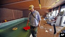 An anti-Gaddafi fighter walks next to a swimming pool in a house belonging to Moammar Gadhafi's son Hannibal, in Tripoli, August 30, 2011