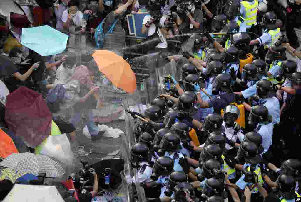 Riot police use pepper spray against protesters after thousands of people block a main road to the financial central district outside the government headquarters in Hong Kong. 