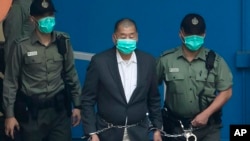 FILE - Jimmy Lai is escorted by Correctional Services officers to get on a prison van before appearing in a court in Hong Kong, Dec. 12, 2020. Hong Kong journalists said Lai's prosecution was "highly damaging" to press freedom.