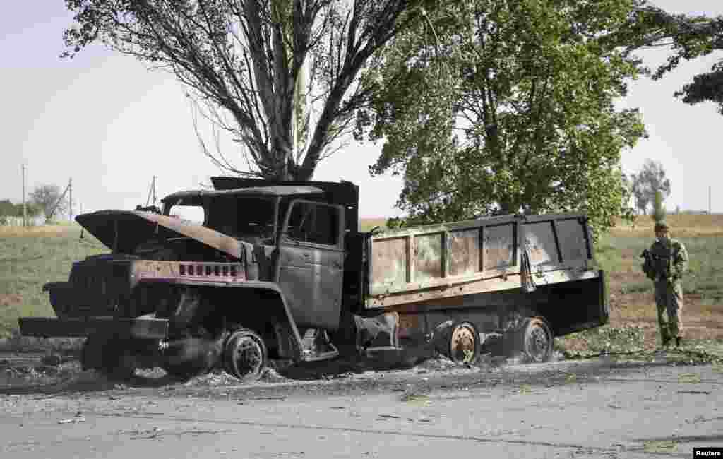 A Ukrainian soldier looks at a truck burned by recent shelling on the outskirts of the southern coastal town of Mariupol, Ukraine, Sept. 7, 2014.  