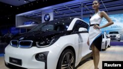 FILE - A model poses beside a BMW i3 during a media presentation during the 36th Bangkok International Motor Show in Bangkok, Thailand, March 24, 2015. 