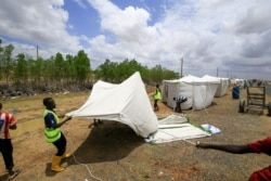 Sudanese men help erect a tent on the side of the road for displaced families, as a result of flooding and torrential rain, in the town of Osaylat, 50 km southeast of the capital Khartoum, Aug. 6, 2020.