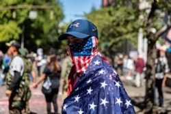 A man dressed in an American flag joins protesters in Portland