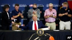 President Donald Trump hands pens out after signing an executive order on commercial fishing after speaking at a round-table discussion with commercial fishermen at Bangor International Airport in Bangor, Maine, June 5, 2020. 