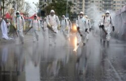 Taiwanese army soldiers wearing protective suits spray disinfectant on a road to prevent community cluster infection, in New Taipei City, Taiwan, March 14, 2020.