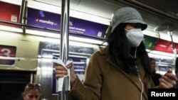 Una mujer con una mascarilla protectora se aferra a un poste del metro con una servilleta en la ciudad de Nueva York, EEUU, el 10 de febrero de 2023. 