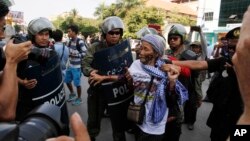 A woman from Boeung Kak Lake community is stopped by local security guards near a blocked main street near the Phnom Penh Municipality Court during villagers' gathering to call for the release of anti-governments protesters who were arrested in a police crackdown, in Phnom Penh, Cambodia, Friday, April 25, 2014. Almost two dozen Cambodian factory workers and rights activists have gone on trial in connection with labor protests earlier this year that rocked Prime Minister Hun Sen's government. (AP Photo/Heng Sinith)