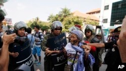 A woman from Boeung Kak Lake community is stopped by local security guards near a blocked main street near the Phnom Penh Municipality Court, April 25, 2014.