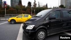 FILE - An Uber driver drives his car with a taxi seen in the background, in Istanbul, Turkey, March 15, 2018.