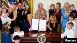 美国总统特朗普在白宫举行的妇女历史月活动上，与第一夫人梅拉尼娅一起展示了一份签署的公告。(2026年3月12日)