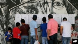 Electores buscan en listados en un puesto de votación en Caracas.