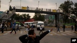 A man jokes with a friend as he sings near a subway station, during the new coronavirus pandemic in Mexico City, Monday, June 1, 2020.