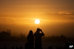 FILE - People gather at "El Morro" to watch the sunset during the San Sebastián Street festivities in San Juan, Puerto Rico, Jan. 21, 2024. (AP Photo/Alejandro Granadillo, File)