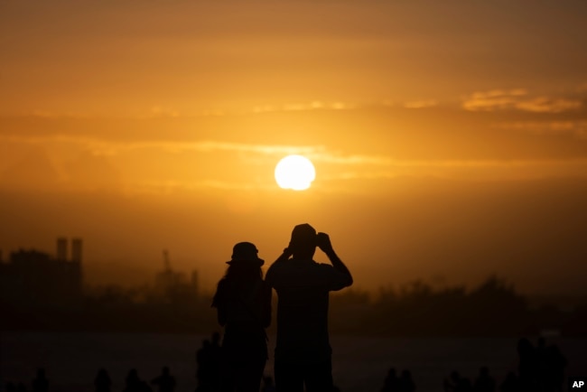 FILE - People gather at "El Morro" to watch the sunset during the San Sebastián Street festivities in San Juan, Puerto Rico, Jan. 21, 2024. (AP Photo/Alejandro Granadillo, File)