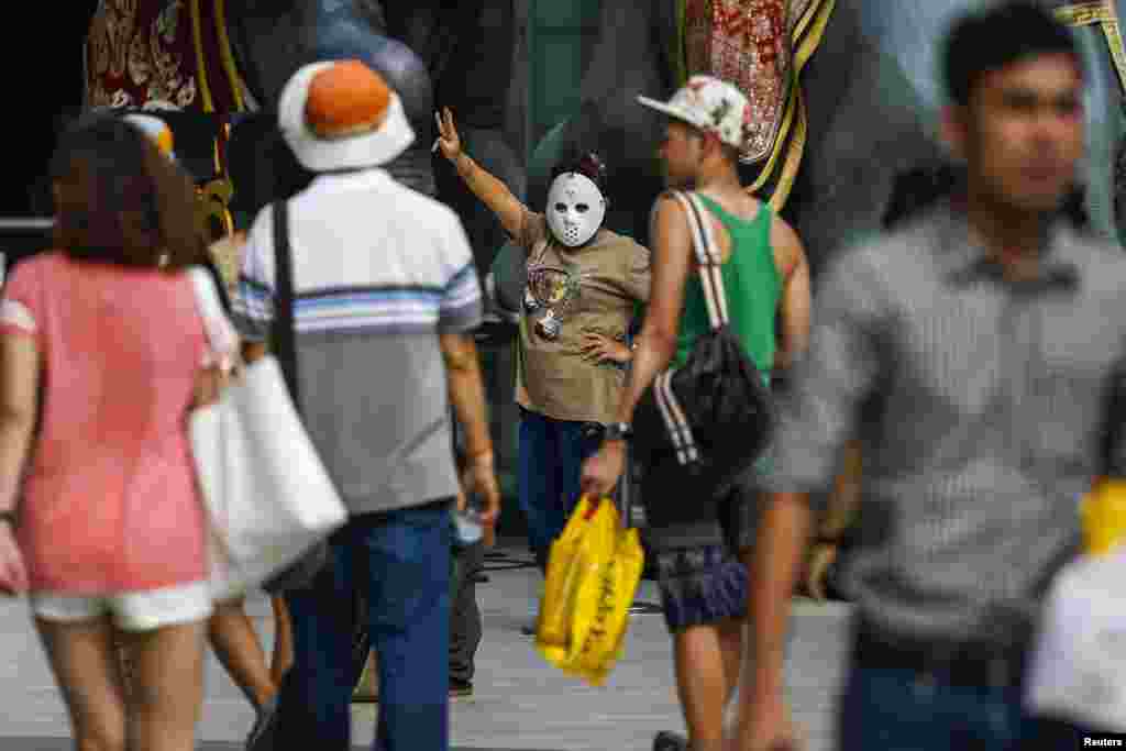 A masked demonstrator gestures during a brief protest against military rule at a shopping mall in Bangkok, June 1, 2014. 