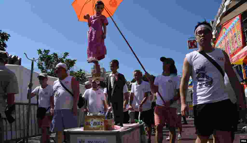 小色芯在列日當空下巡遊有工作人員撐傘遮太陽。(美國之音湯惠芸拍攝)