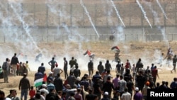 Palestinian demonstrators run for cover from tear gas canisters fired by Israeli forces during a protest marking the 71st anniversary of the 'Nakba', or catastrophe, near the Israel-Gaza border fence, east of Gaza City, May 15, 2019. 